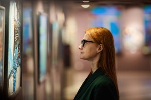 Femme rousse admirant une œuvre d'art et l'analysant