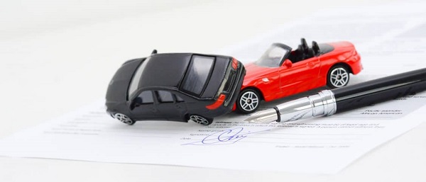 Deux petites figurines de voitures accidentées sur un contrat d'assurance